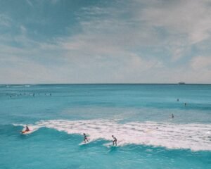 Surfers riding waves on the stunning Waikiki Beach in Hawaii, vibrant blue waters.