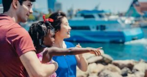 Multicultural family enjoying a sunny day by the waterfront, pointing at boats.